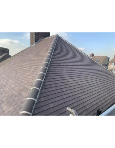 Brown tiled roof with chimney and blue sky.