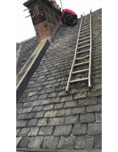 Person repairing chimney on roof with ladder